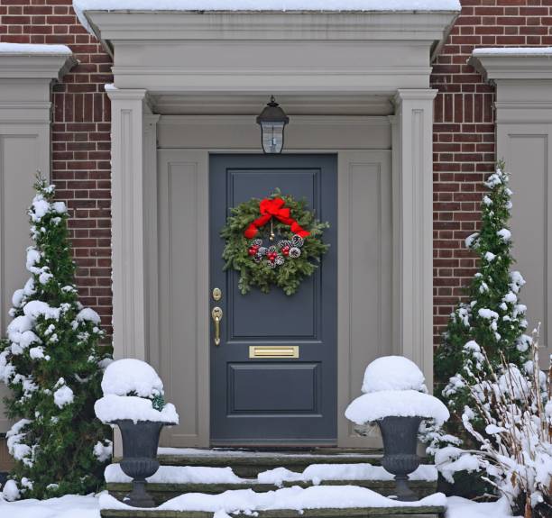 istock Front door with pine cone Christmas wreath with snow covered steps 1291100454