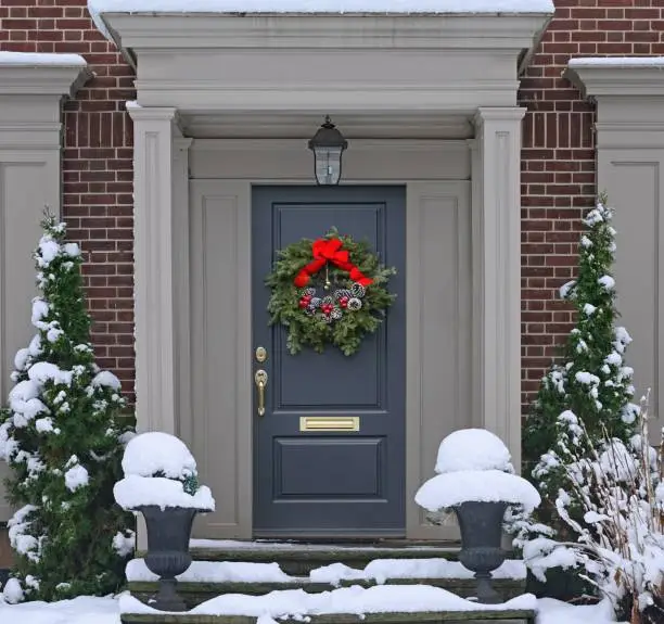 Photo of Front door with pine cone Christmas wreath with snow covered steps