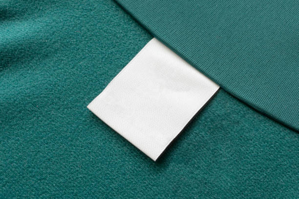 пустой белый прачечная одежды этикетки на зеленом фоне текстуры ткани - label textile shirt stitch стоковые фото и изображения