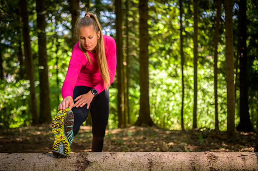Young adult female athlete stretching muscles before running in nature. Healthy lifestyle concept.