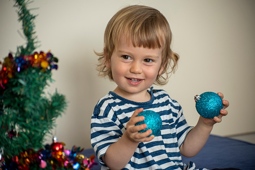 2 year old boy helps set up Christmas decorations in Australia.