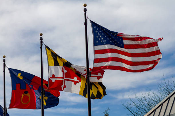 Flags of the USA, state of Maryland and Montgomery County Threeflags are vawing on seperate flags poles against blue sky on a windy day. From right to left they stand for: USA, state of Maryland and Montgomery County maryland state colors stock pictures, royalty-free photos & images