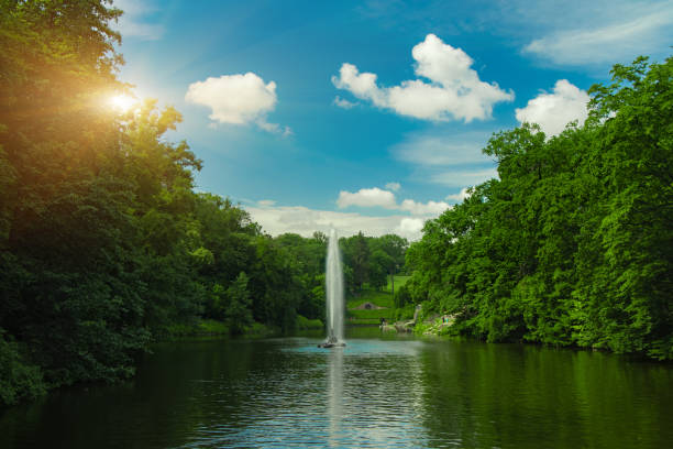 idyllic park outdoor landscape scenic environment space view pond with fountain in spring April clear weather day time and yellow sun light glare wallpaper picture concept idyllic park outdoor landscape scenic environment space view pond with fountain in spring April clear weather day time and yellow sun light glare wallpaper picture concept pond fountains stock pictures, royalty-free photos & images