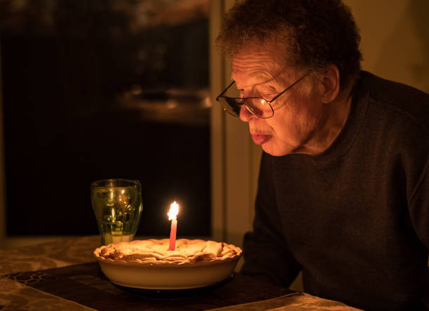 istock Older man blowing candle on his birthday cake 1291134414