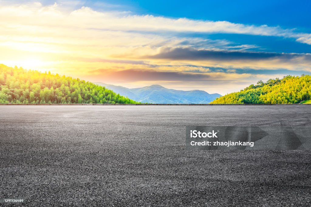 Asphalt road and green mountain with bamboo forest landscape. Asphalt road and green mountain with bamboo forest natural landscape at sunset. Parking Lot Stock Photo