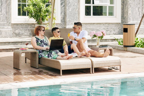 istock Family relaxing by swimming pool 1291137538