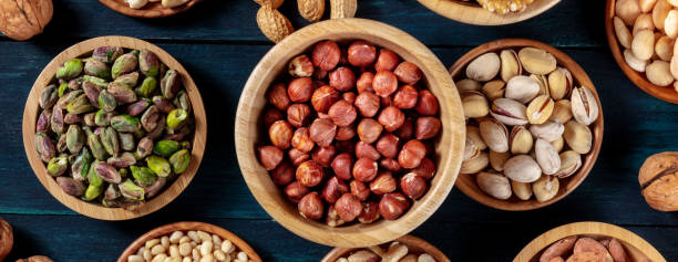istock Nuts assortment panorama on a dark background. Hazelnuts and pistachios, almonds and pine nuts 1291139698
