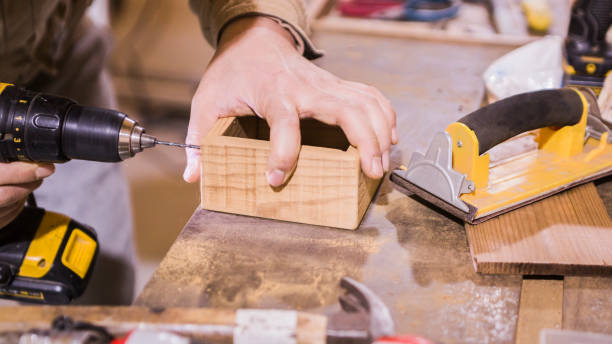 istock The master works in a studio and drill a hole in a wooden board. 1291140759