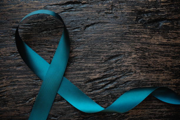 Top view of teal ribbon on dark background with copy space. Cervical and ovarian cancer, sexual assault, pcos, ptsd, anxiety disorder, agoraphobia and scleroderma awareness concept. Top view of teal ribbon on dark background with copy space. Cervical and ovarian cancer, sexual assault, pcos, ptsd, anxiety disorder, agoraphobia and scleroderma awareness concept. polycystic ovary syndrome photos stock pictures, royalty-free photos & images