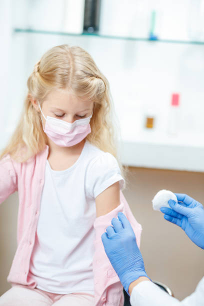 istock Girl with protective face mask looking at her arm disinfected for vaccination 1291142112