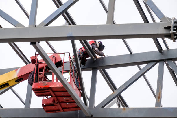 Man welder working on a crane performs high-rise work on welding metal structures of a new tower at a height. Isolated on white background.