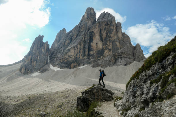 istock Oberbachernspitze - A man with big backpack and sticks, hiking in high Italian Dolomites. There are many sharp peaks in front 1291144969