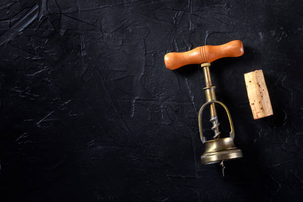 istock Wine tasting concept. A vintage corkscrew and a cork, shot from above on a black background 1291147150