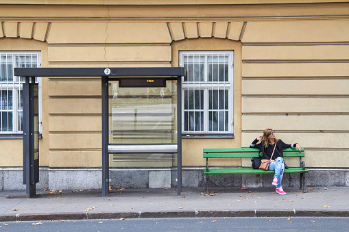 Young caucasian woman waiting for a public transportation on a station.