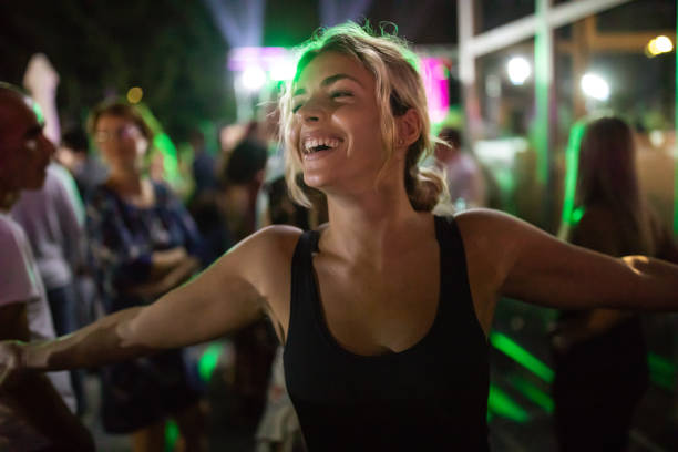 Enjoying nightlife Beautiful young woman dancing in a crowded nigh outdoor party club concert stock pictures, royalty-free photos & images