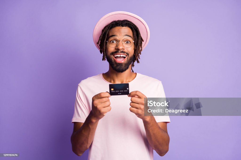 Photo portrait of excited guy holding credit card in two hands isolated on vivid violet colored background Photo portrait of excited guy holding credit card in two hands isolated on vivid violet colored background. Credit Card Stock Photo