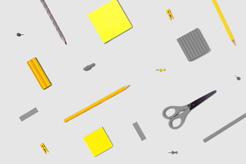 Flat lay photo with stikers, pencils, scissors, plasticine, clothespins, paper clips in yellow and gray colors.