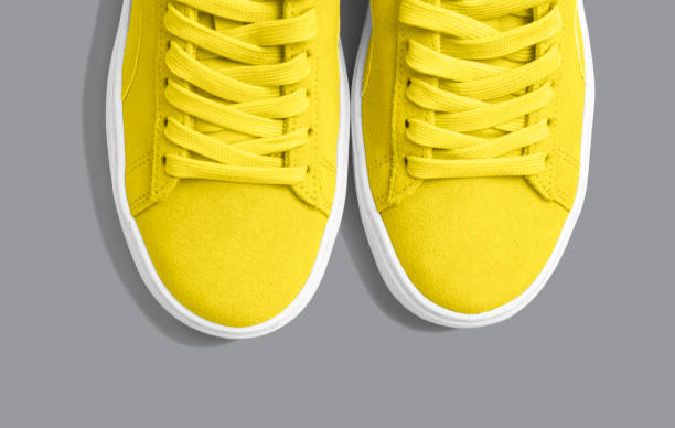 Female yellow sneakers on trendy gray background close up, top view. Female yellow sneakers on a trendy gray background close up, top view. yellow shoes stock pictures, royalty-free photos & images