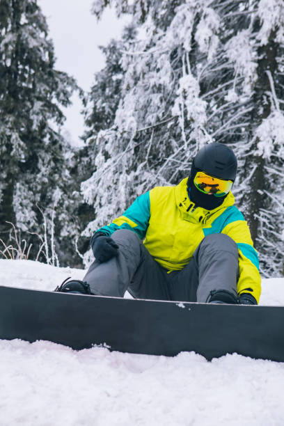 istock man sitting on snowed ground with snowboard 1291154196