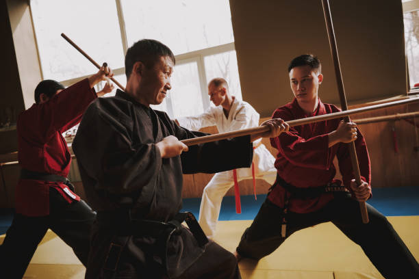 istock Martial arts fighters in different colors keikogi fighting with sticks. 1291154265
