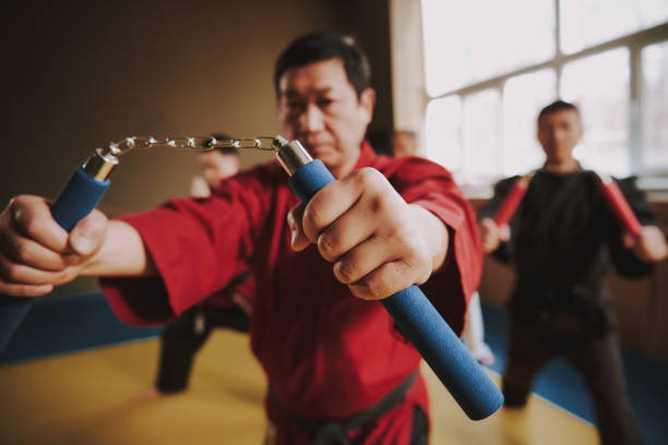 martial arts fighters in different colors keikogi training with nunchuck. - nunchaku imagens e fotografias de stock