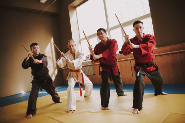 istock Martial arts fighters in different colors keikogi training with sticks. 1291154304