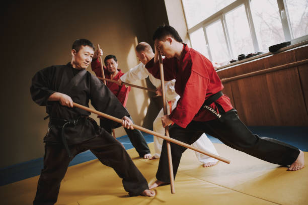 istock Martial arts fighters in different colors keikogi fighting with sticks. 1291154335