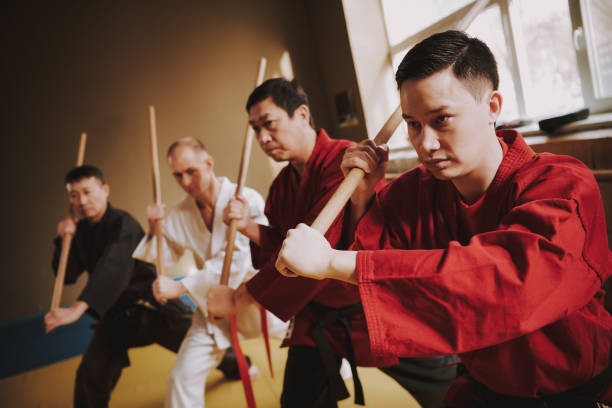istock Martial arts fighters in different colors keikogi fighting with sticks. 1291154347