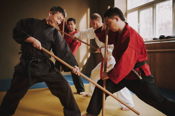 istock Martial arts fighters in different colors keikogi fighting with sticks. 1291154477