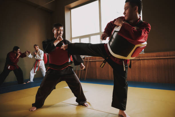 istock Martial arts fighters in different colors keikogi training with protective gear. 1291154641