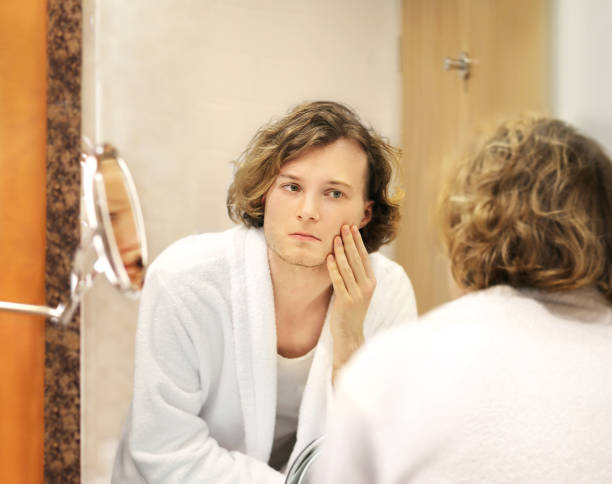 istock Applying the cream.young man looking in the mirror 1291157228