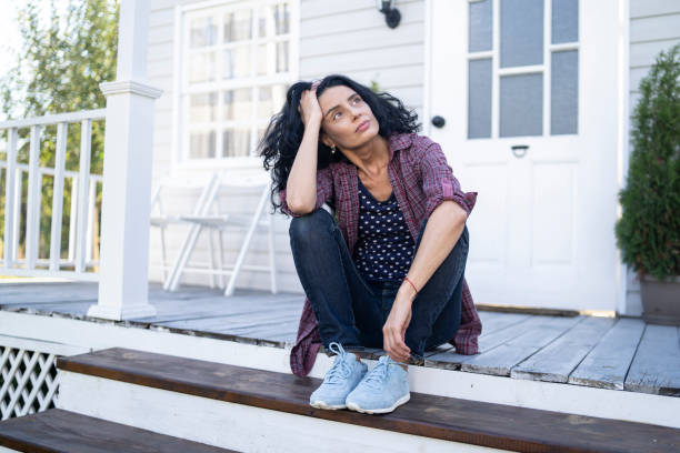 istock Sad woman sitting alone in front of her porch 1291157310