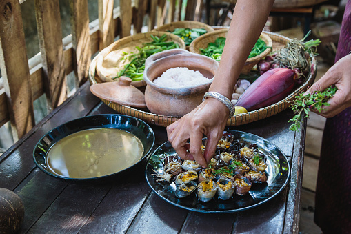 Hand of Asian women preparing and cooking home made grill field crabs and vegetables at traditional Thai kitchen, Northeast thailand (Isan) healthy foods concept