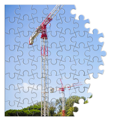 Metal tower crane, colored in white and red, against a blue background -  concept image in jigsaw puzzle shape.