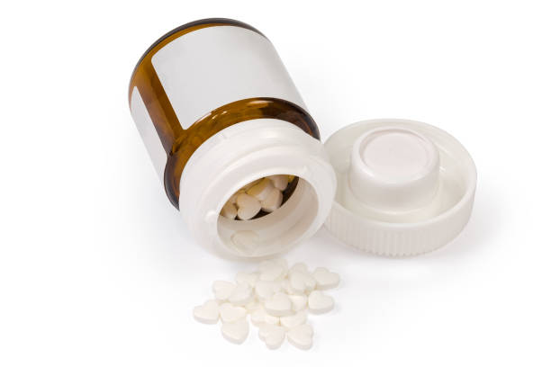 istock White heart shaped pills in glass pill container and beside 1291162688