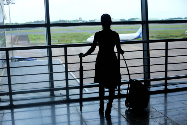 Rear view of young women standing in airport, Dabolim Airport, Goa Silhouette of standing young Indian women in Dabolim airport, Goa, India. india airport stock pictures, royalty-free photos & images