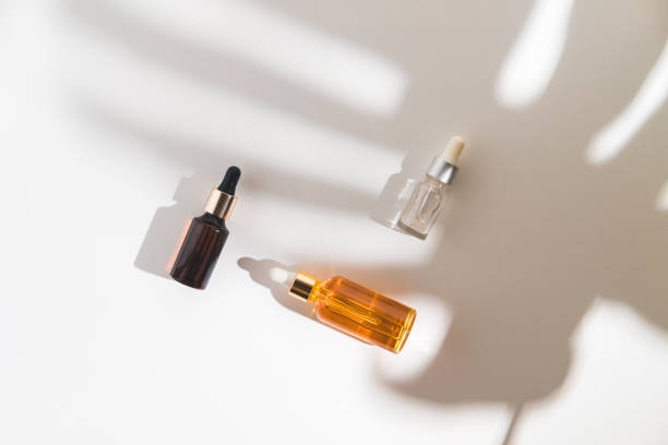 istock White, orange and black serum bottles on white background. Trending shadow from a palm branch. Cosmetic mockup. Place to insert text, images. Top view. Flat lay. 1291167036