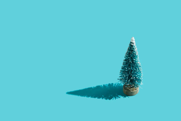 istock Toy plastic green Christmas tree on minimal blue background with hard shadow. Christmas and New Year background for congratulations on the coming holidays. Flat lay. Top view. Place for text. 1291167102