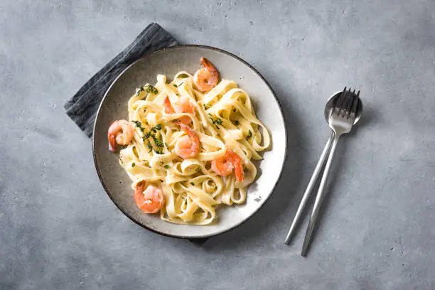 Shrimp fetticcine pasta. Italian pasta with shrimps and cream alfredo sauce, top view, copy space.