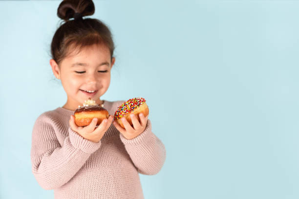 istock Little happy cute girl holding donuts on blue background 1291170645