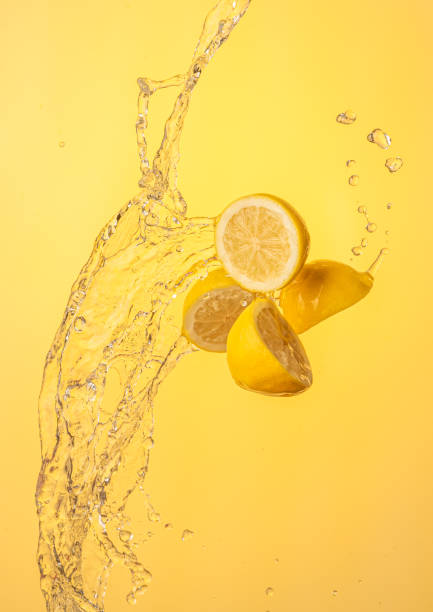 istock Lemon halves splashing in mid air against yellow background 1291173165