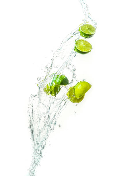 istock Fresh limes with water splash in midair, isolated on white background 1291173235