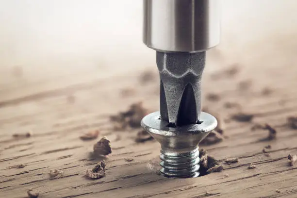 Photo of screwdriver screw in a wood oaks plank