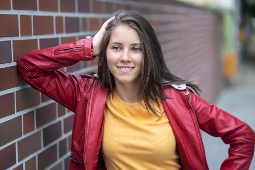 Smiling teenage girl standing in front of a brick wall