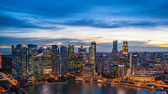 Singapore skyline view during sunset from aerial point of view. Many multi-colored lights illuminates the city.