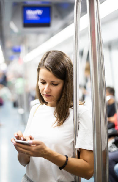 istock Woman using phone in subway car 1291180294