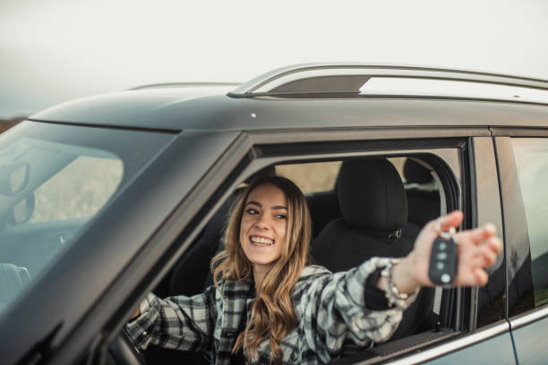 istock Young woman holding car keys inside a car 1291180372