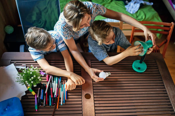 Mother and kids saving energy by changing bulbs