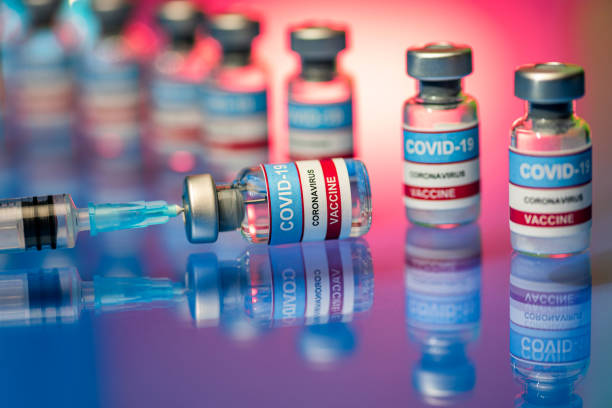 Vials and Syringe - Close up of Covid-19 vaccine on a reflective surface stock photo