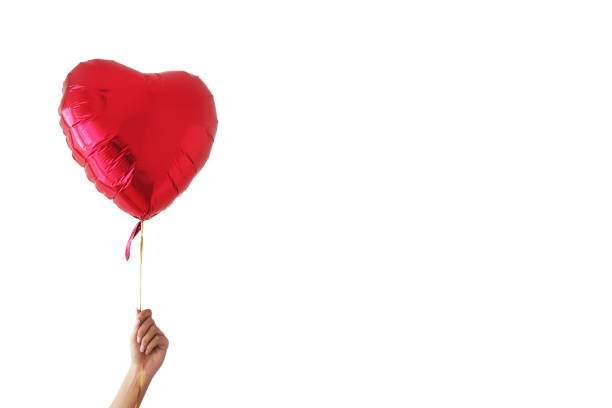 A hand holding a heart-shaped red glossy balloon on a white background